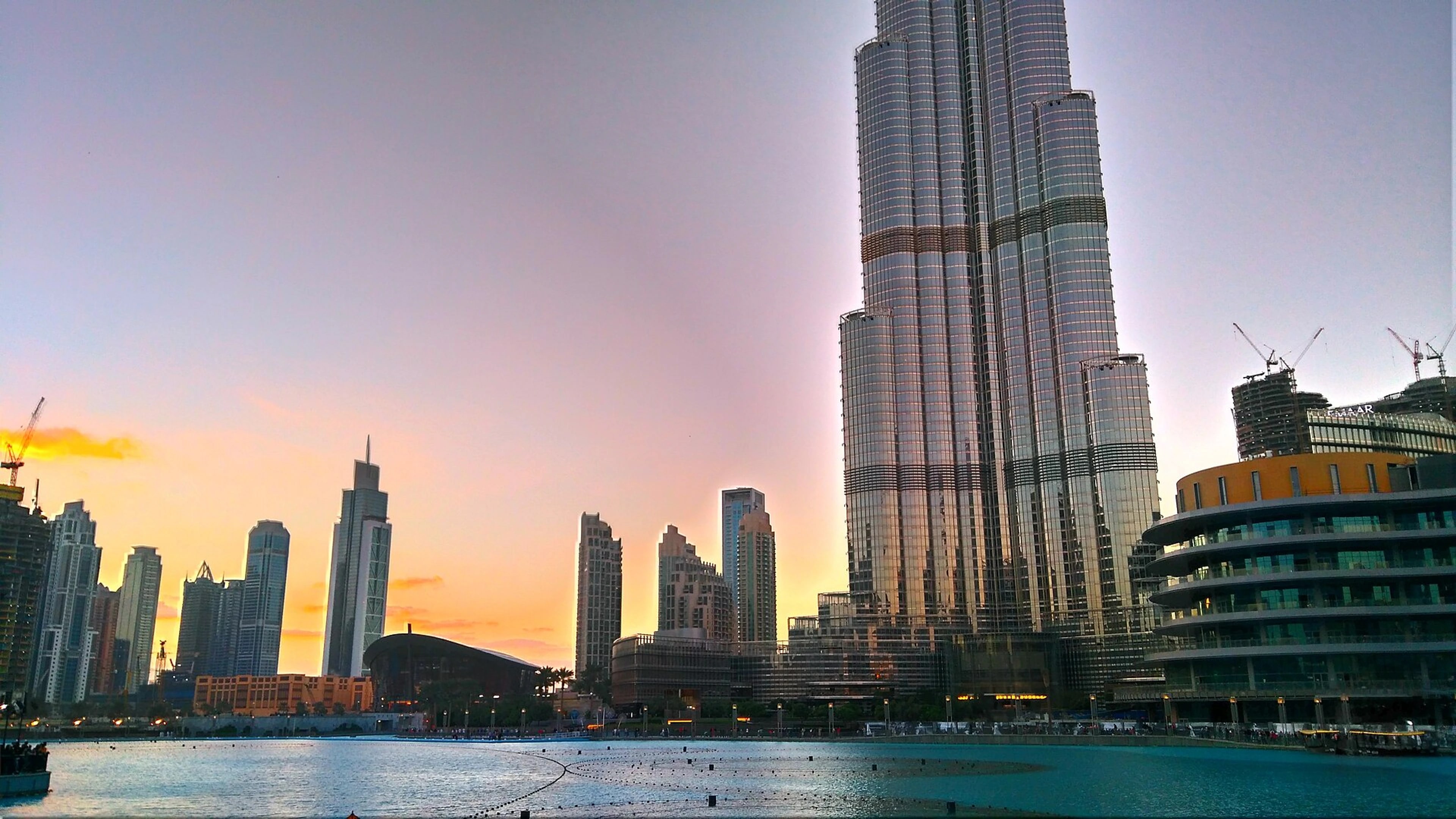 Burj Khalifa and the Dubai Fountain lake in Downtown Dubai at sunset.