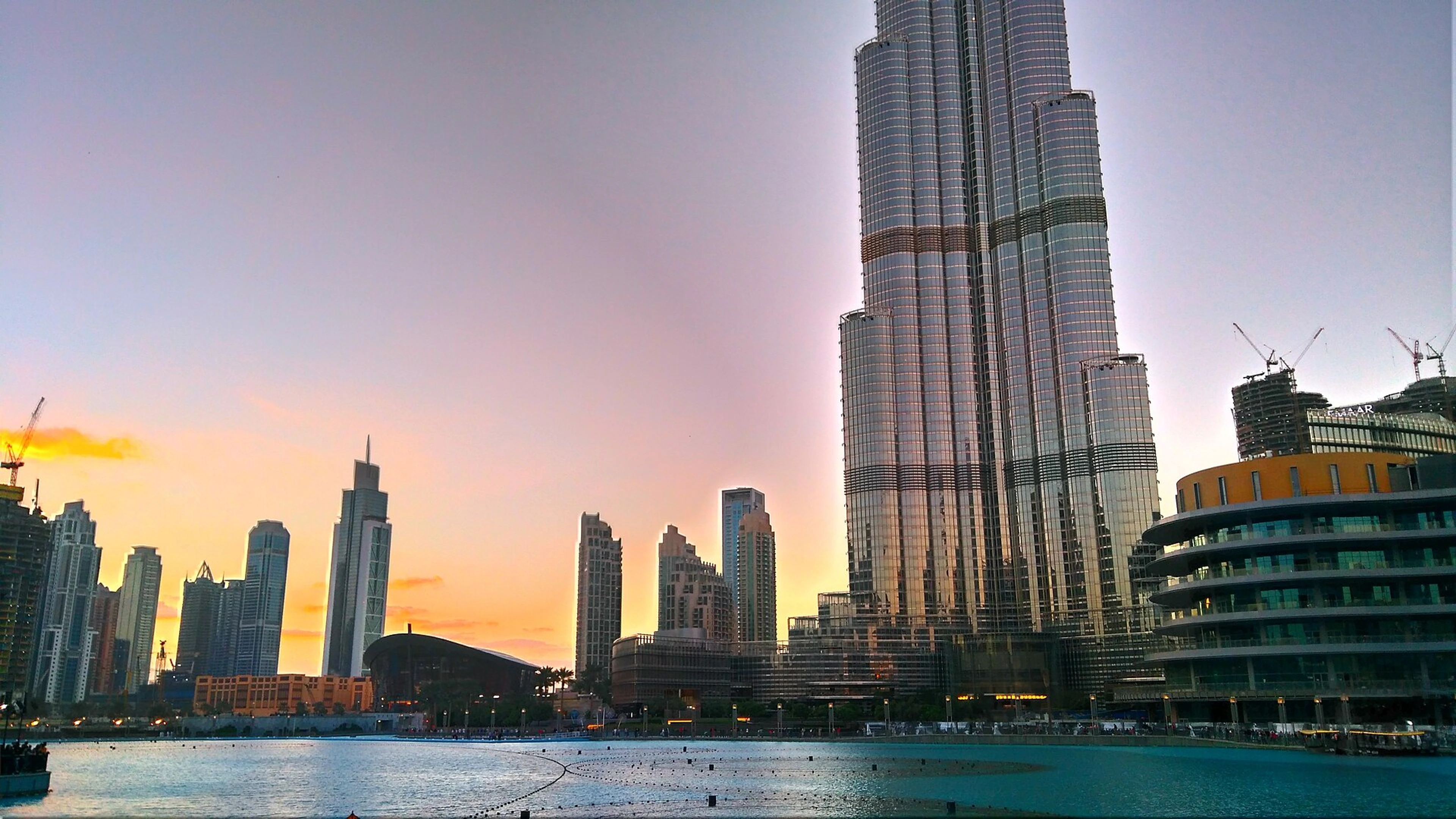 Burj Khalifa and the Dubai Fountain lake in Downtown Dubai at sunset.