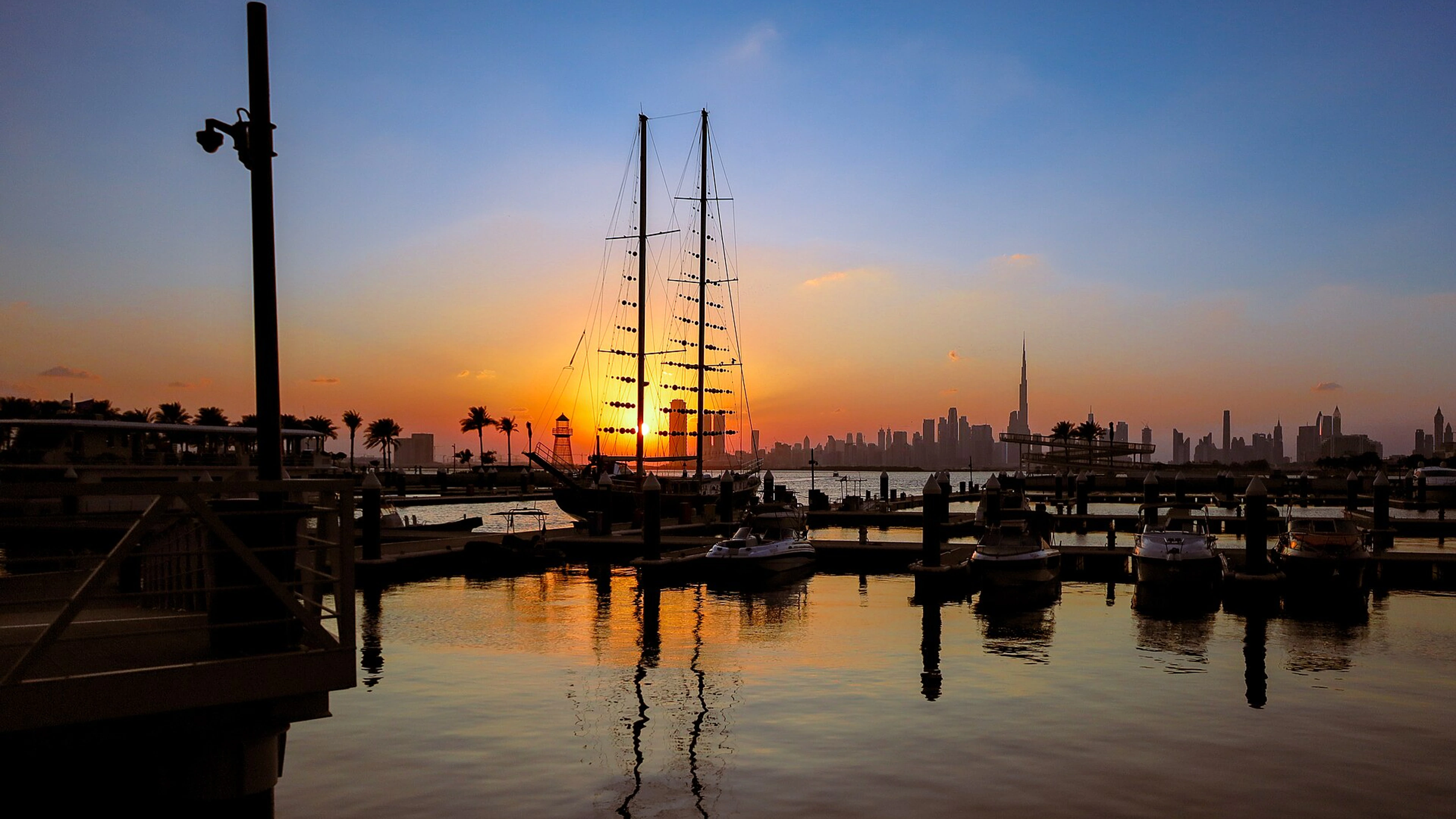 Sailing boat and marina at Dubai Creek Harbour at sunset, with the Downtown skyline beyond.