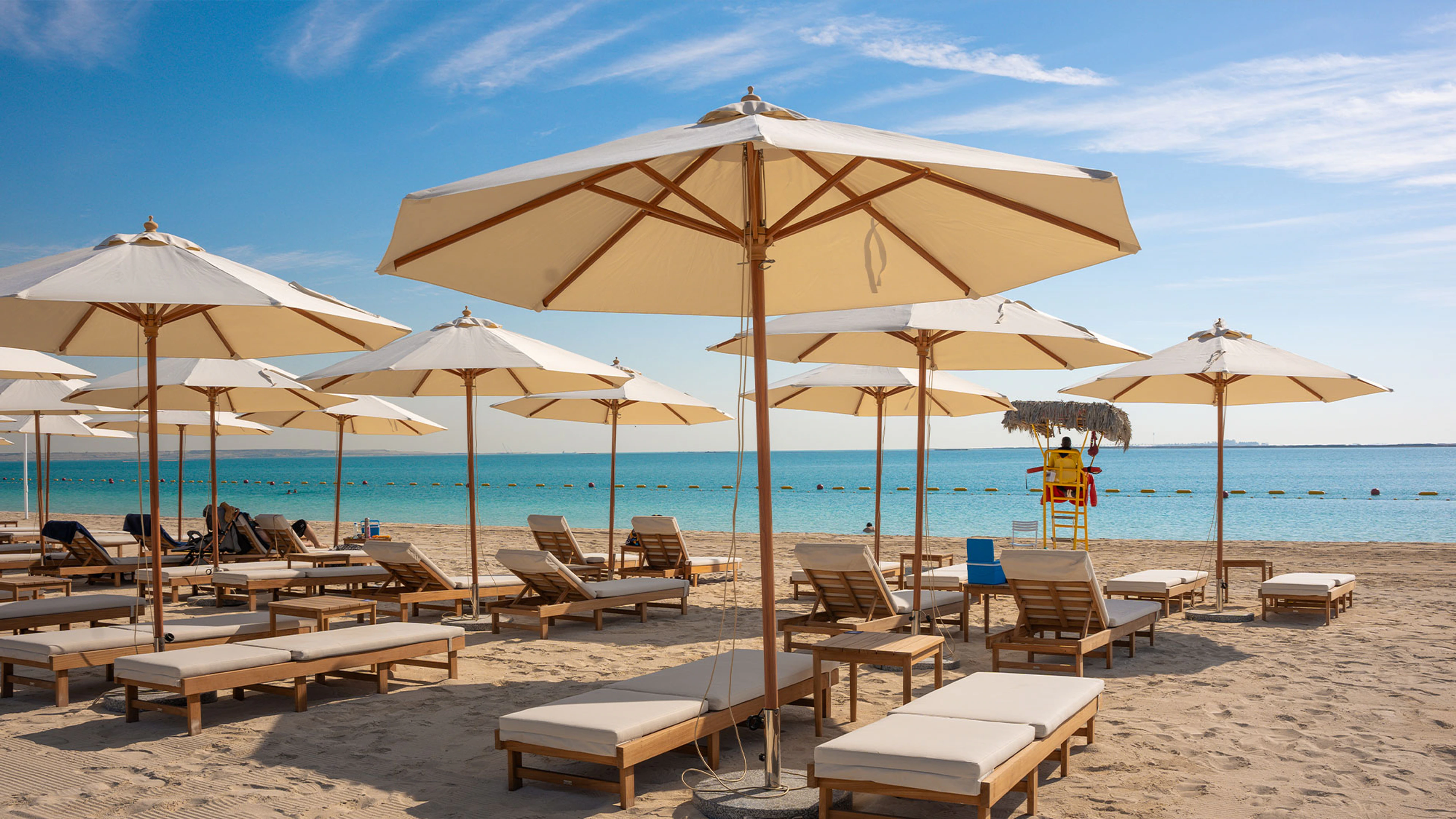 Beach umbrellas, loungers and shoreline at Marsana on Hudayriyat Island, Abu Dhabi.