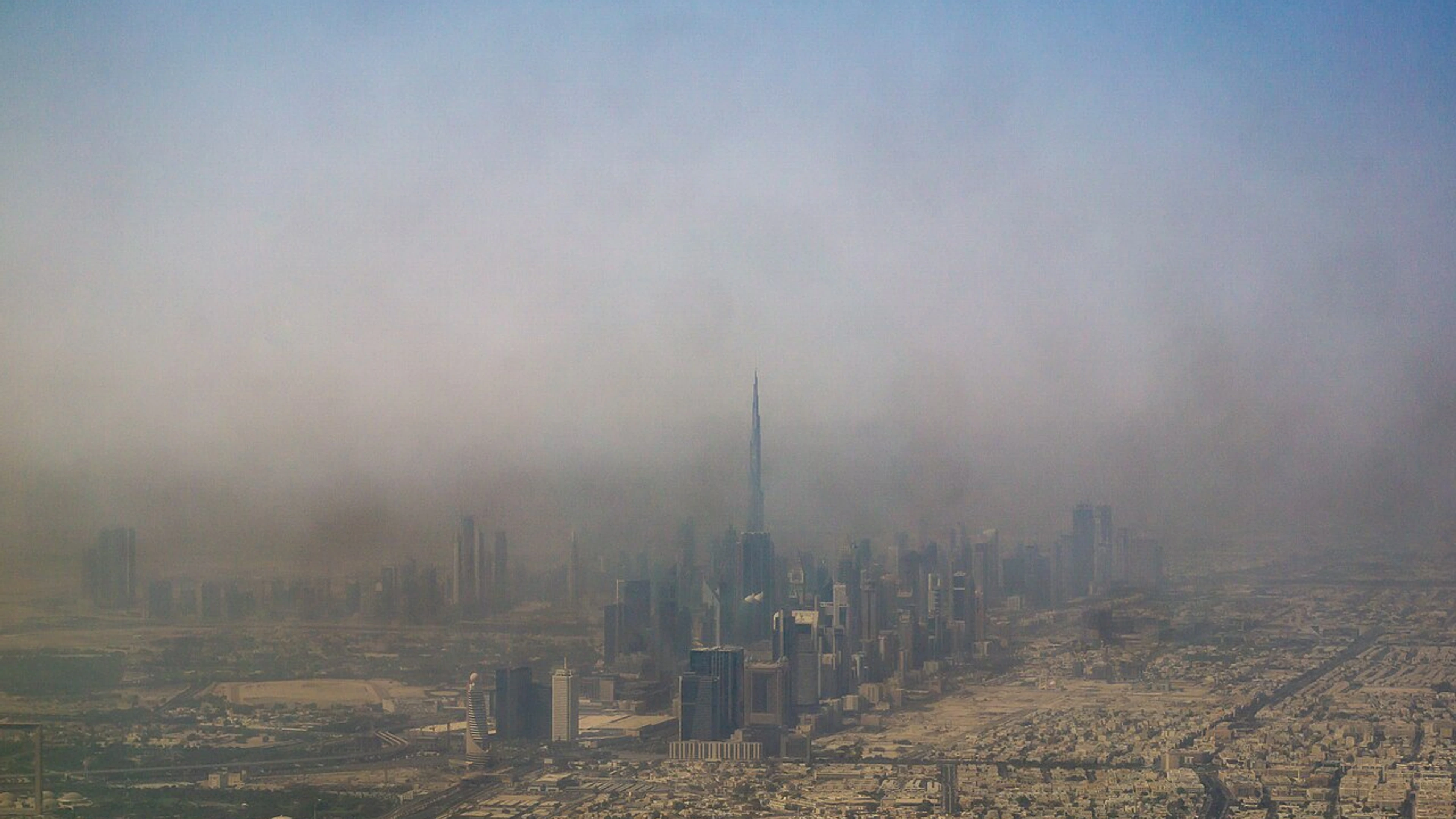 Dubai skyline centred on Burj Khalifa, an Emaar landmark, viewed through haze.